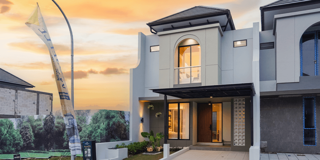Modern two-story house with large glass windows at sunset, landscaped garden and a sales banner in front of the property.